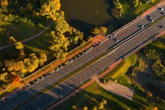 View from the height of the road with cars near the autumn Park.