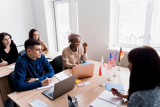 Foreign school private study with a school girl. Teacher explain grammar of native language using laptop. Prepearing to exam with tutor. English, British, German and Poland flags in front.