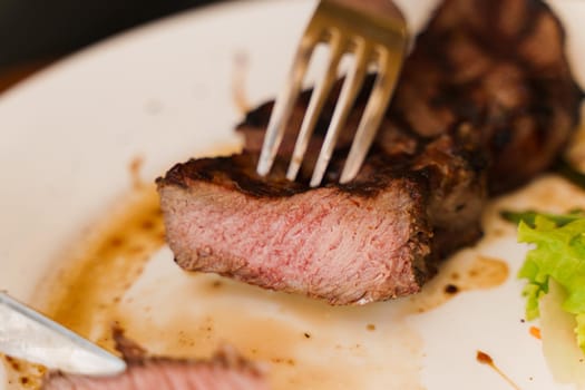 Steak on white plate on the on wooden table. Medium-rare juicy meat.