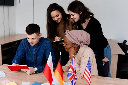 English class study with students from diffent countries: Poland, Germany, USA. Teamwork. Working in multiethnic students. Teacher study foreign languages together in class. Studing with laptop.