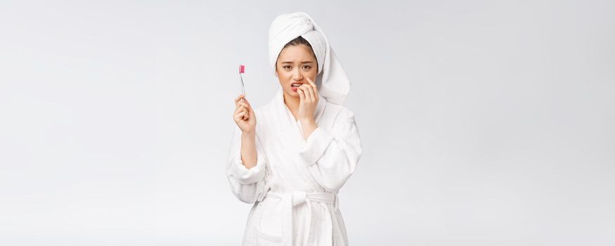 Unhappy beautiful woman brushing her teeth on white background.