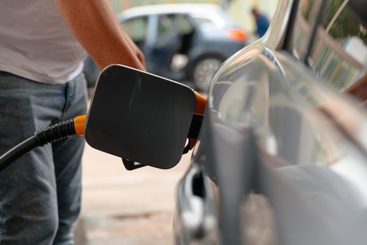 Refuel cars at the fuel pump. The driver hands, refuel and pump the car's gasoline with fuel at the petrol station. Car refueling at a gas station Gas station