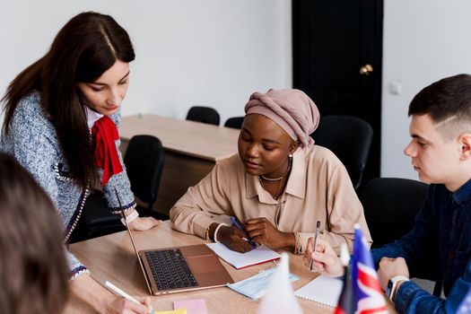 Teamwork. Working in multiethnic group of students. teacher study foreign languages together in class. Studing with laptop. Black handsome girl student study with white people together