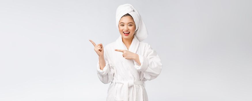 Beauty portrait of young woman showing and pointing finger to empty copy space, asian beauty in bathrobe