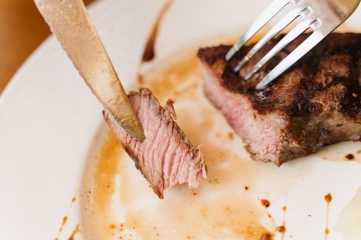 Steak on white plate on the on wooden table. Medium-rare juicy meat.