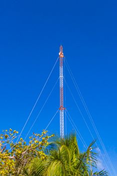 Red white 5G tower with blue sky background radiation kills us in Tulum in Mexico.