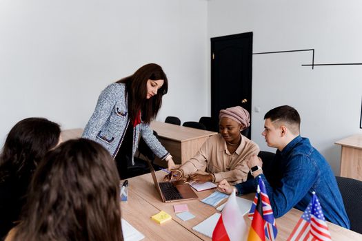 Foreign school private study with a school girl. Teacher explain grammar of native language using laptop. Prepearing to exam with tutor. English, British, German and Poland flags in front.