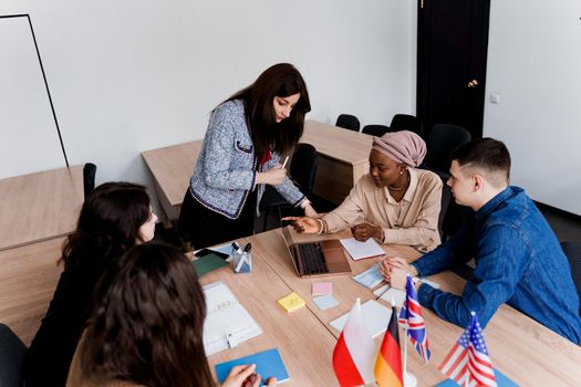 Teamwork. Working in multiethnic group of students. teacher study foreign languages together in class. Studing with laptop. Black handsome girl student study with white people together