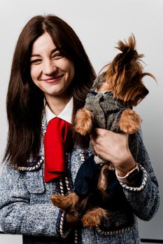 Girl holds brown dog isolated on white background. Young attractive woman with dog yorkshire terrier smiles. Close up photo. Pet care. People and pets.