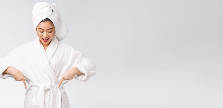 Beauty portrait of young woman showing and pointing finger to empty copy space, asian beauty in bathrobe