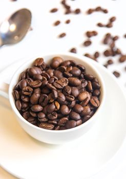 white cup and coffee beans on a white background. Selective focus.