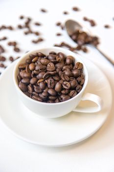 white cup and coffee beans on a white background. Selective focus.