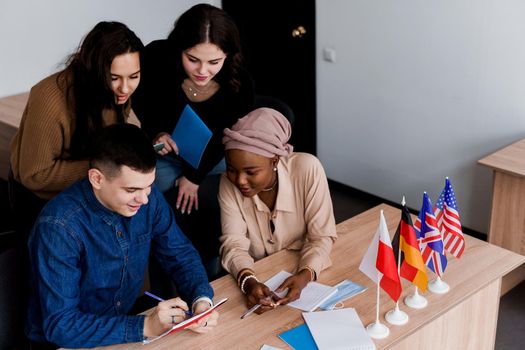 English class study with students from diffent countries: Poland, Germany, USA. Teamwork. Working in multiethnic students. Teacher study foreign languages together in class. Studing with laptop.