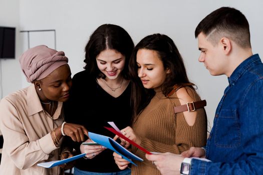 Multiethnic students and teacher study foreign languages together in class. Studing with notebook. Black attractive girl student study with white people together and look into camera