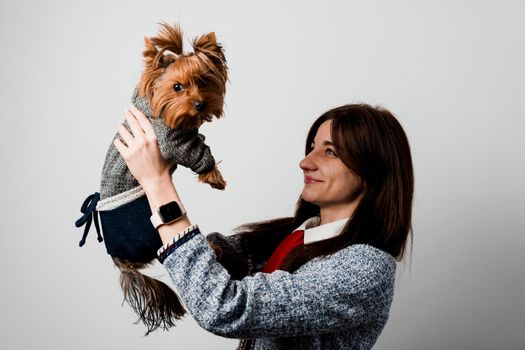 Young attractive woman with dog yorkshire terrier smiles. Close up photo. Pet care. People and pets. Girl holds brown dog isolated on white background