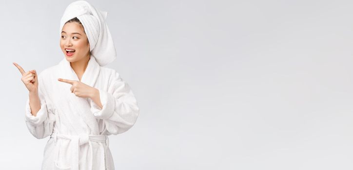 Beauty portrait of young woman showing and pointing finger to empty copy space, asian beauty in bathrobe