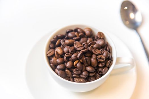 white cup and coffee beans on a white background. Selective focus.