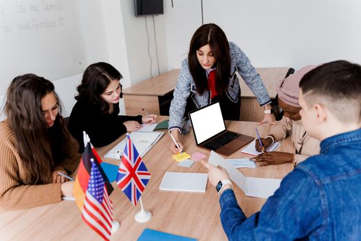 Teamwork. Working in multiethnic group of students. teacher study foreign languages together in class. Studing with laptop. Black handsome girl student study with white people together