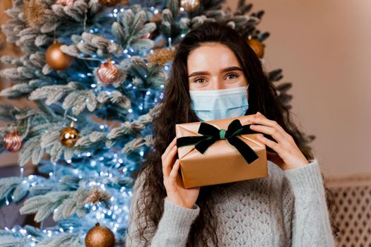 Girl in a medical mask with a Christmas present. celebration of the new year on self-isolation. Pandemic coronavirus covid-19 concept
