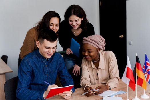 English class study with students from diffent countries: Poland, Germany, USA. Teamwork. Working in multiethnic students. Teacher study foreign languages together in class. Studing with laptop.