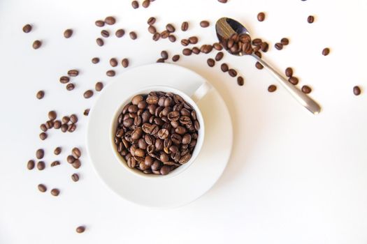 white cup and coffee beans on a white background. Selective focus.