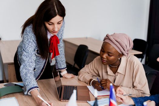 Teamwork. Working in multiethnic group of students. teacher study foreign languages together in class. Studing with laptop. Black handsome girl student study with white people together