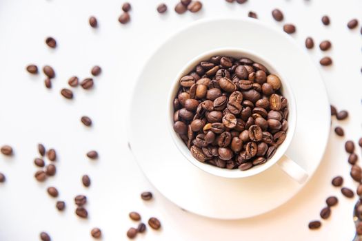 white cup and coffee beans on a white background. Selective focus.