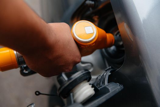 Man filling gasoline fuel in car holding pump. Closeup on male hand refuel car. The concept of increasing fuel prices.