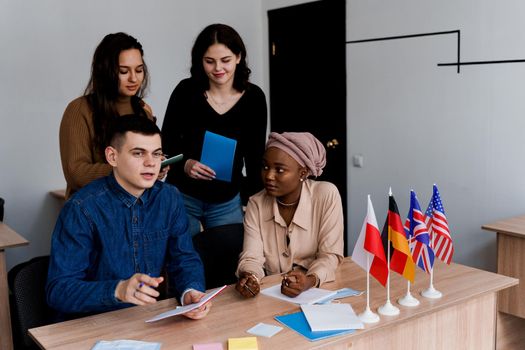 English class study with students from diffent countries: Poland, Germany, USA. Teamwork. Working in multiethnic students. Teacher study foreign languages together in class. Studing with laptop.