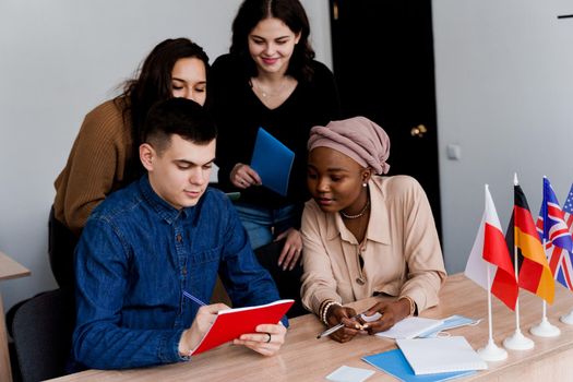 English class study with students from diffent countries: Poland, Germany, USA. Teamwork. Working in multiethnic students. Teacher study foreign languages together in class. Studing with laptop.