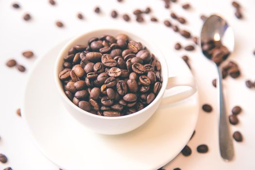 white cup and coffee beans on a white background. Selective focus.