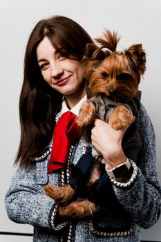 Girl holds brown dog isolated on white background. Young attractive woman with dog yorkshire terrier smiles. Close up photo. Pet care. People and pets.