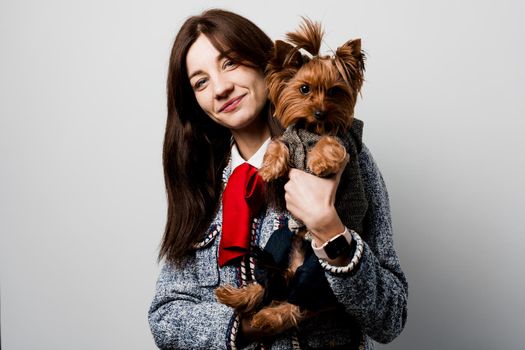 Girl holds brown dog isolated on white background. Young attractive woman with dog yorkshire terrier smiles. Close up photo. Pet care. People and pets.