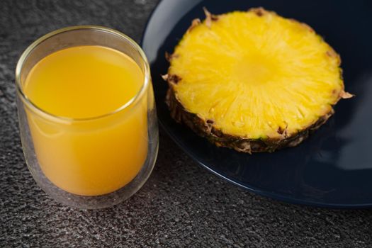 Piece of pineapple tropical fruit and yellow juice on dark background