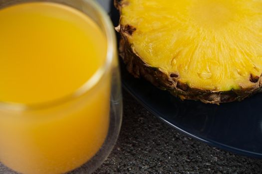 Piece of pineapple tropical fruit and yellow juice on dark background