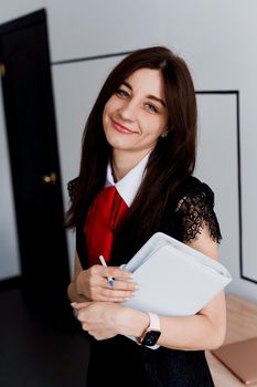 Portrait of a beautiful smiling student with notebook on bright background. Happy female teacher smiling.