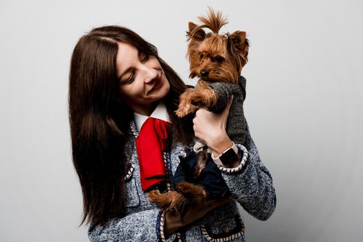 Girl holds brown dog isolated on white background. Young attractive woman with dog yorkshire terrier smiles. Close up photo. Pet care. People and pets.