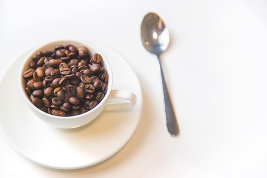 white cup and coffee beans on a white background. Selective focus.