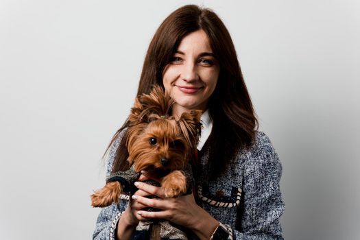 Young attractive woman with dog yorkshire terrier smiles. Close up photo. Pet care. People and pets. Girl holds brown dog isolated on white background