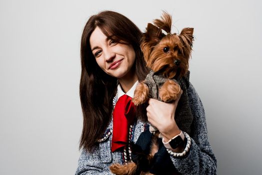 Girl holds brown dog isolated on white background. Young attractive woman with dog yorkshire terrier smiles. Close up photo. Pet care. People and pets.