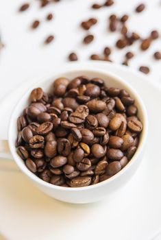 white cup and coffee beans on a white background. Selective focus.