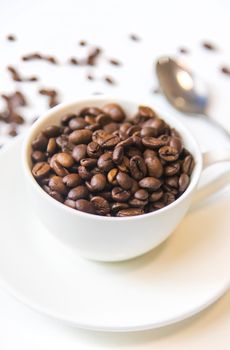white cup and coffee beans on a white background. Selective focus.