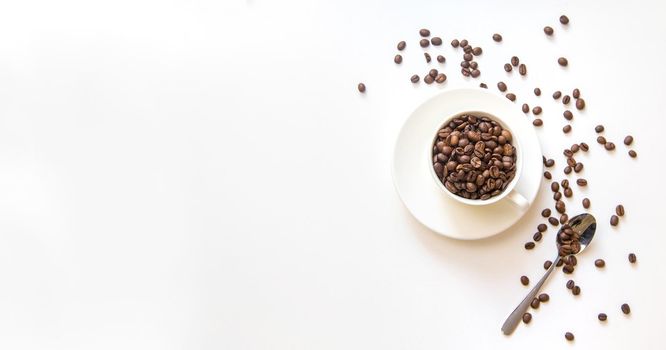 white cup and coffee beans on a white background. Selective focus.