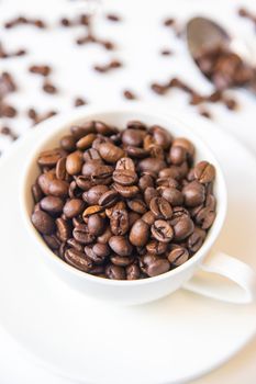 white cup and coffee beans on a white background. Selective focus.