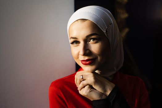 Muslim girl is praying at home. Close-up portrait of muslim model weared in traditional islamic scarf. Islam religion