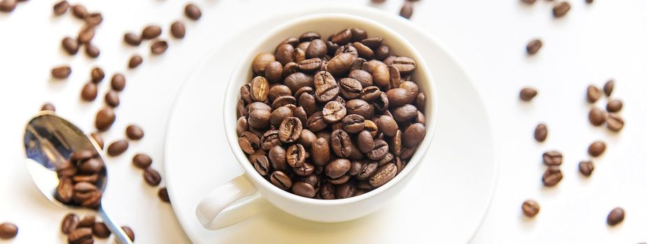 white cup and coffee beans on a white background. Selective focus.