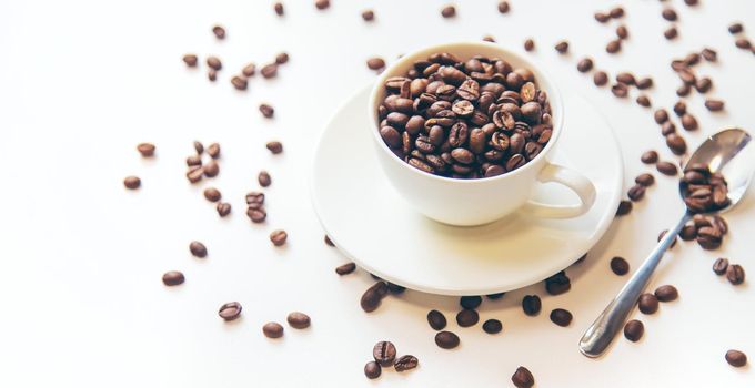 white cup and coffee beans on a white background. Selective focus.