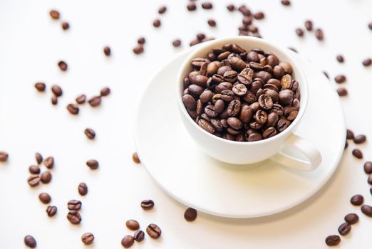 white cup and coffee beans on a white background. Selective focus.