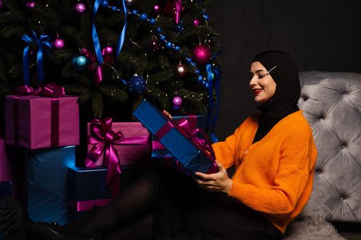 Muslim woman with gift near new year tree. Christmas celebration of islam religion people