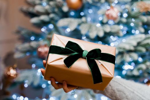 Christmas gift in hands close-up. present for girl. Young beautiful woman near the New Year tree. New Year Sale Advertising for Online Stores